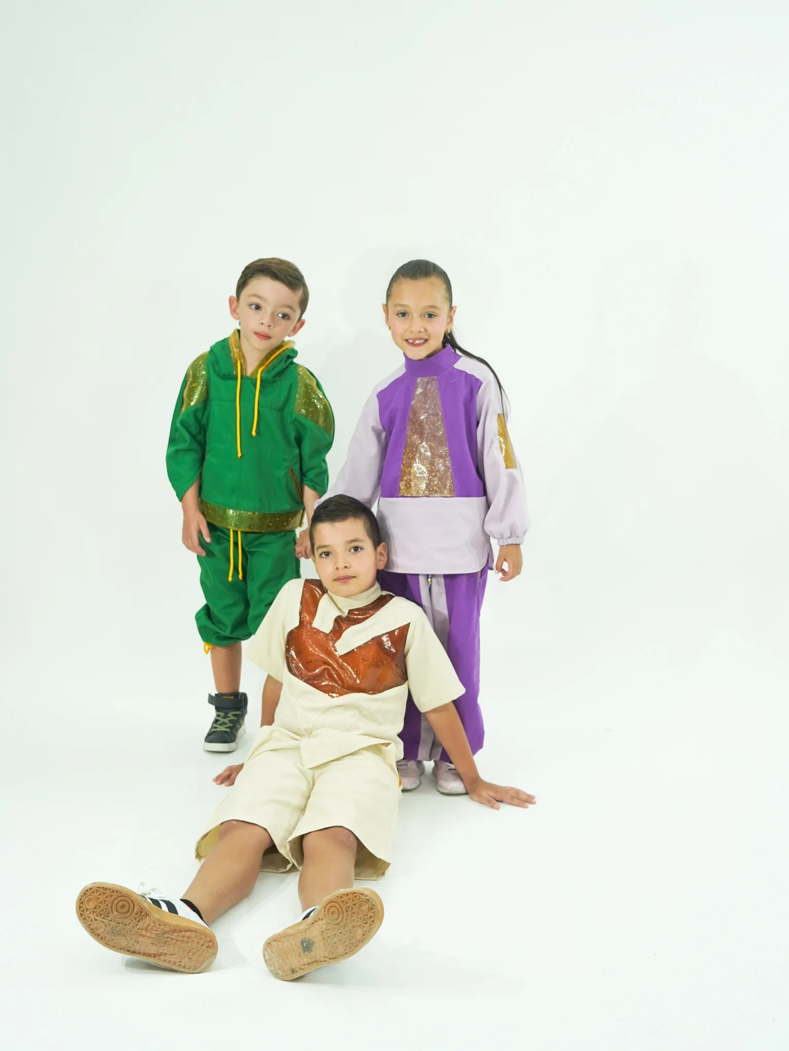 Tres niños con las prendas del proyecto Materia en juego